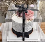 Pink-flower cake in a clear pickup box with a black ribbon